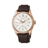 The Seiko Presage Automatic 38mm Watch HCC008J features a pearl-white "shironeri" dial with a wave pattern and pearl-painted finish. The 38mm pink-gold-coloured stainless steel case is fitted with a domed crystal.