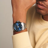 The Longines Conquest Men's 43mm Stainless Steel Quartz Watch L3.760.4.96.6 worn on the wrist, showing its sporty size and fit. The sunray blue dial and stainless steel bracelet give it a versatile look for both everyday and dressier outfits.