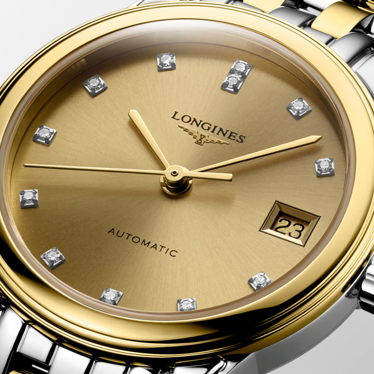 Close-up of the gold-tone dial on the Longines Flagship Classic Automatic Women’s 26mm Watch L4.274.3.37.7. The detail shows the hour markers, hands and date window beneath scratch-resistant sapphire crystal with anti-reflective coating.