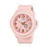 Casio Baby-G+PLUS BGA15K-4A front view, featuring the round pastel pink matte resin case with shimmering metal dial, Arabic numerals at 12 and 6 o'clock, rotating seven-design day display, three analogue hands, and matching pastel pink matte band — shown as a wristwatch with detachable silicone holder included.