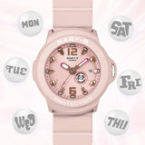 Casio Baby-G+PLUS BGA15K-4A front view, featuring the round pastel pink matte resin case with shimmering metal dial, Arabic numerals at 12 and 6 o'clock, rotating seven-design day display, three analogue hands, and matching pastel pink matte band