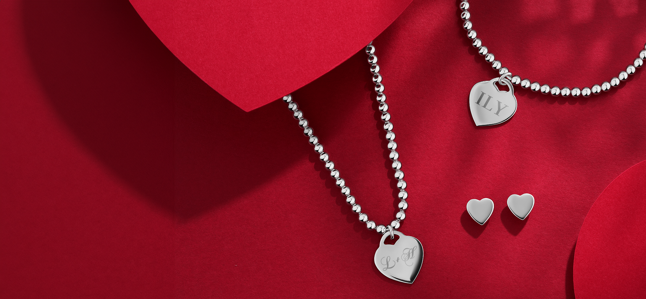 Silver jewelry set with heart-shaped charms on a red background