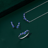 Front-on view of three Wallace Bishop Created Sapphire & Lab-Grown Diamond Chevron pieces in Sterling Silver: the 0.04 TDW Pendant, reference LG34SAP03, the 0.04 TDW Climber Earrings, reference LG34SAP04, and the 0.04 TDW Ring, reference LG38SAP02O. Each piece features round dark blue created sapphires with small round lab-grown diamonds set between them.