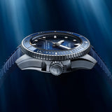 Tissot Seastar 2000 44mm T120.907.17.041.00 with a blue dial, blue bezel, and textured blue strap, shown against a dark blue underwater-like background with light rays.