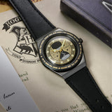 The Timex x Harry Potter Time Turner Quartz 36mm Watch TW2Y76000 is shown beside a gold Time-Turner pendant and Hogwarts-themed papers. The black strap and gold hourglass dial suit Harry Potter fans and collectors.