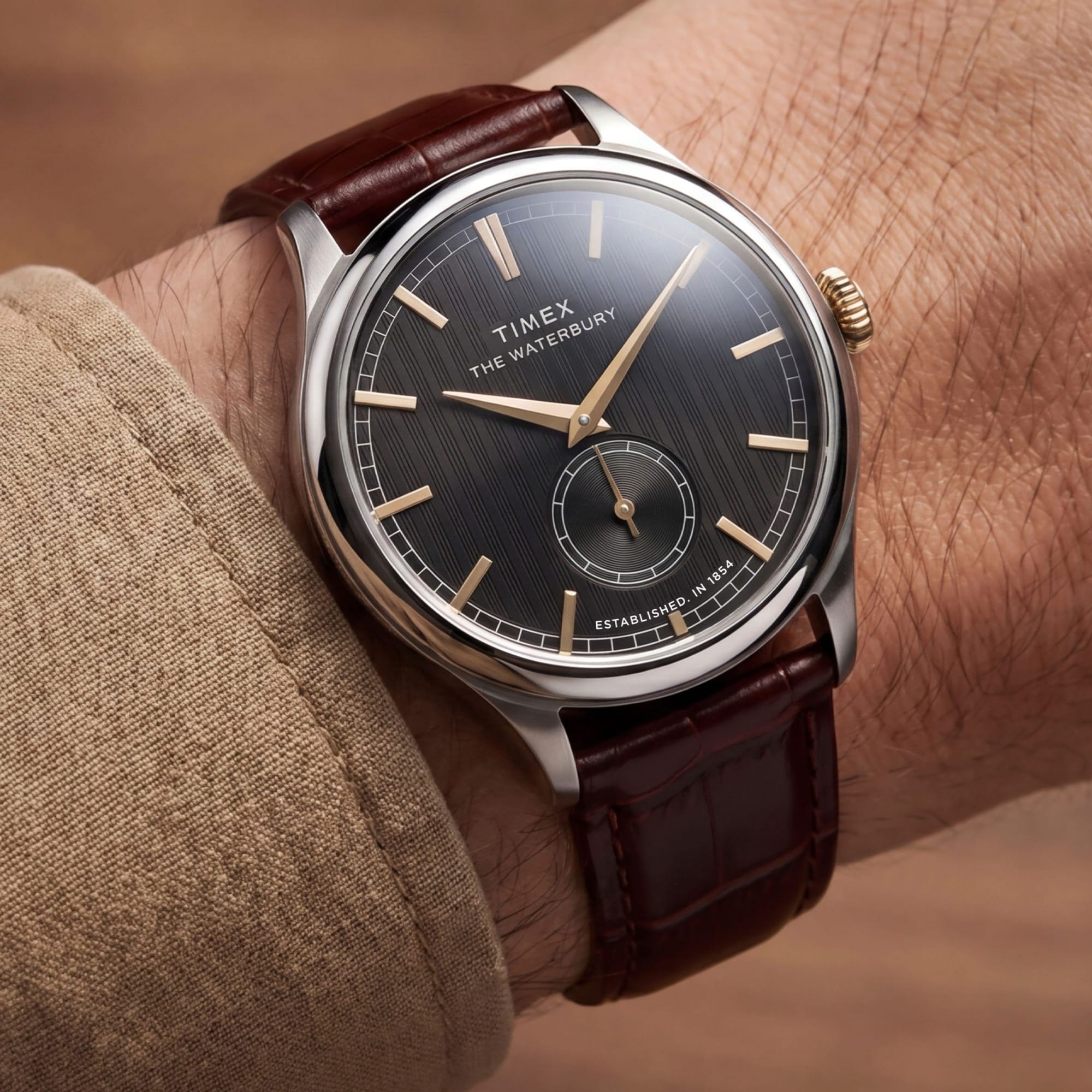 The Timex Waterbury Traditional Quartz 39mm Watch TW2Y92100 pairs its polished silver-tone stainless steel case with a brown leather strap for a classic, considered look. The gold-tone accents add contrast against the black dial.