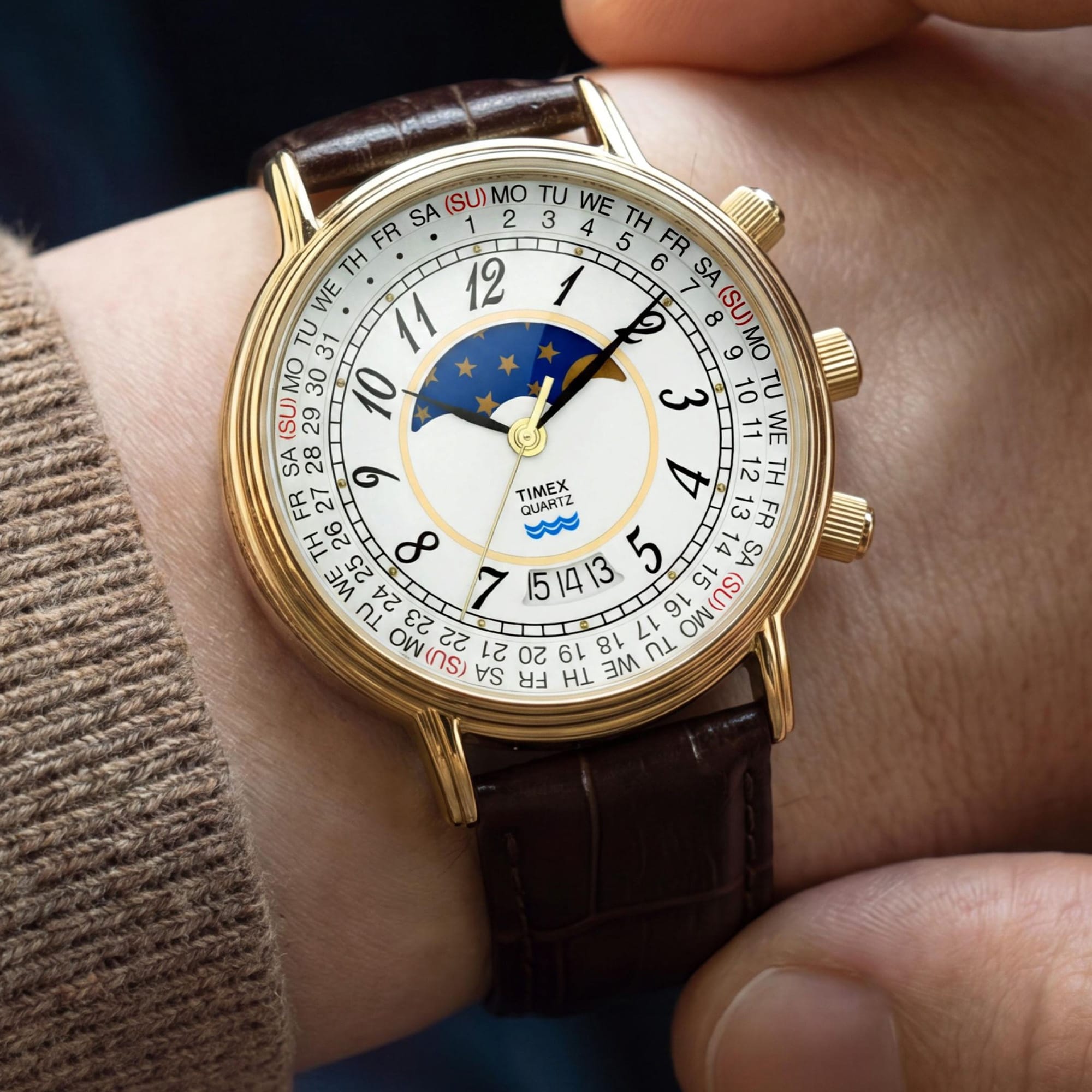 The Timex 1990 Reissue Moon Phase Quartz 37mm Watch TW2Y99000 pairs its gold-tone case with a brown crocodile-grain leather strap for a classic, considered look.