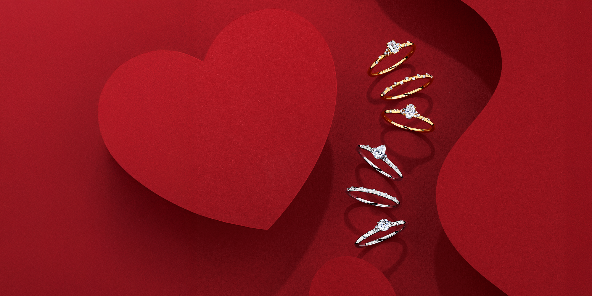 Heart-shaped box with diamond rings on a red background