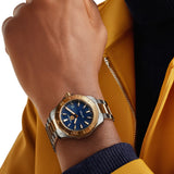 TAG Heuer Aquaracer Professional 200 Solargraph WBP1120.BB0002 shown worn on the wrist, illustrating the case proportions and two-tone bracelet fit. The blue dial stands out against the yellow jacket sleeve in frame.