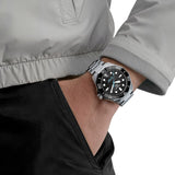 TAG Heuer Aquaracer Professional 300 Date WBP5110.BA0013 shown worn on the wrist, illustrating the case proportions and steel bracelet fit. The black dial stands out against the dark jacket sleeve in frame.