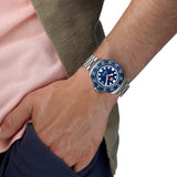 TAG Heuer Formula 1 Solargraph WBY1112.BA0042 shown worn on the wrist, illustrating the case proportions and steel bracelet fit. The blue dial stands out against the pink sleeve in frame.