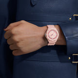 TAG Heuer Formula 1 Solargraph WBY1165.FT8115 shown worn on the wrist in a second lifestyle shot, illustrating the strap fit from a different angle. The pastel pink dial contrasts against the dark navy sleeve in frame.