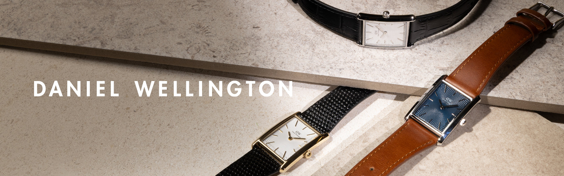 Daniel Wellington watches displayed on a stone surface with 'Daniel Wellington' branding.