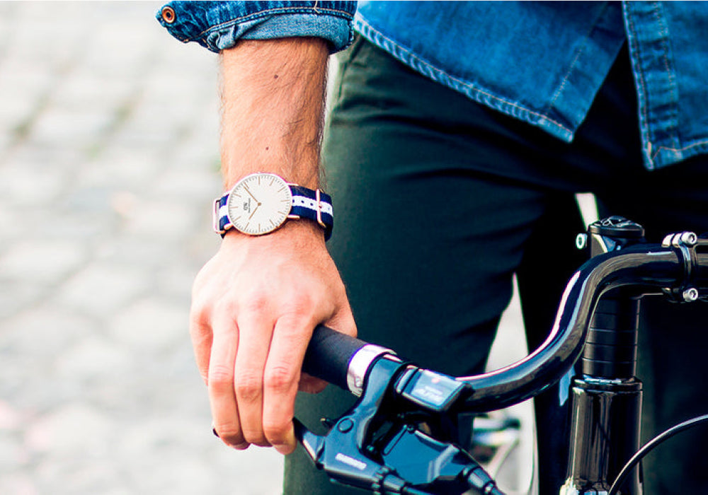 Person holding bicycle handlebars with a Daniel Wellington watch on wrist