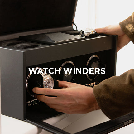 Person using a watch winder with multiple watches inside, labeled 'Watch Winders'.