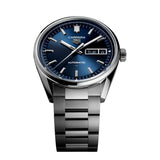 TAG Heuer Carrera Day-Date WDA2112.BA0043 photographed at an angle highlighting the blue dial's day-date window and curved flange. The steel bracelet curves away from the lugs, showing its link construction.
