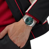 TAG Heuer Carrera Day-Date WDA2115.BA0043 shown worn on the wrist, illustrating the case proportions and steel bracelet fit. The green dial stands out against the sleeve in frame.