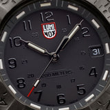 Close-up of the black dial on the Luminox Navy SEAL Foundation Men’s 43mm Quartz Watch XS.3228.NSF, showing the luminous hands, markers and date window at 3 o’clock. This Navy SEAL Foundation 3220 Series watch features ice blue and golden yellow self-powered tritium tubes.
