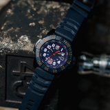 Luminox Navy SEAL Red Bull Ampol Racing Edition Men's 46mm Quartz Watch XS.3501.ARB.N shown in a motorsport-inspired setting. This limited edition Navy SEAL 3500 Series dive watch features a blue dial, a lightweight CARBONOX™ case and 200m water resistance.
