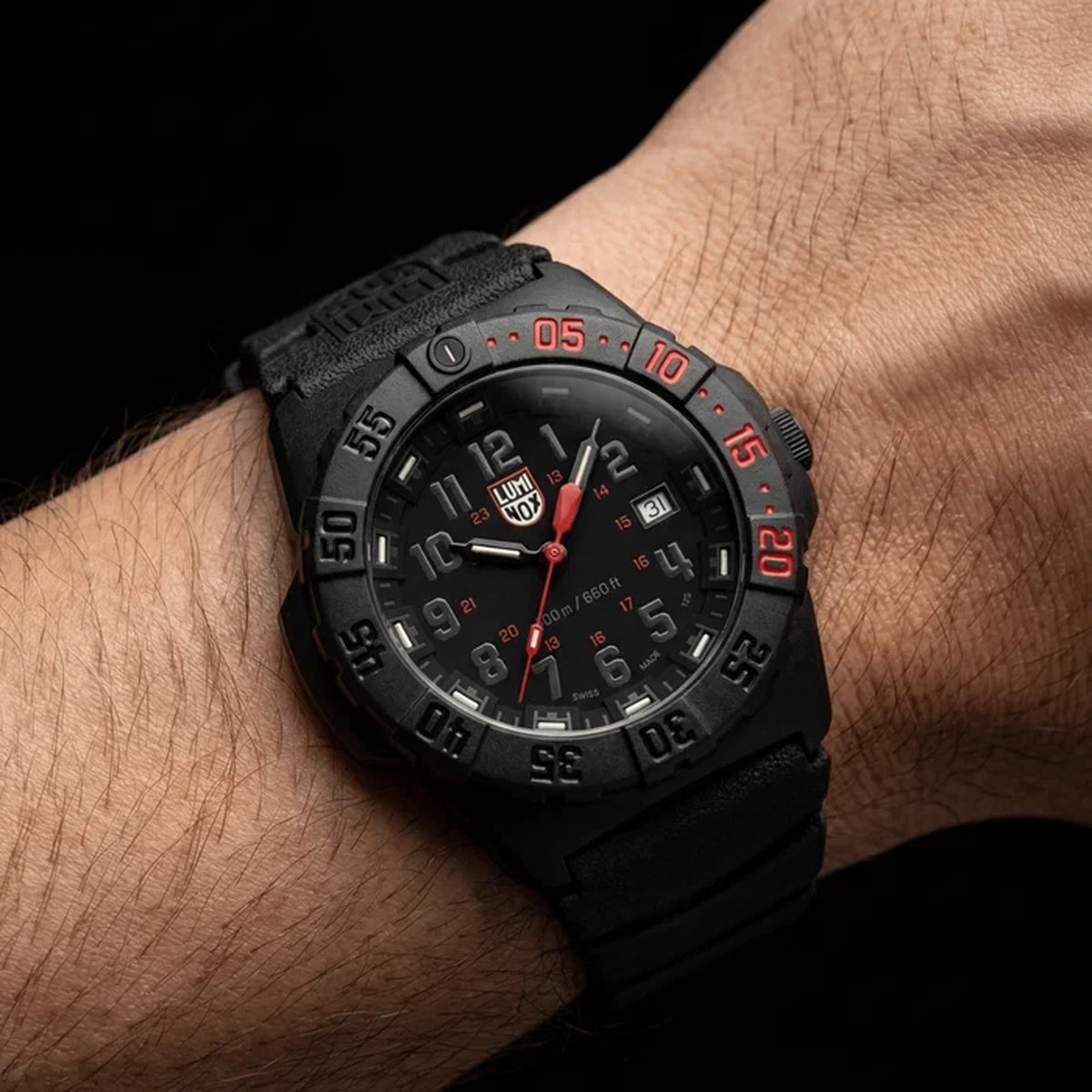 Luminox Navy SEAL 3550 Men’s 44mm Quartz Watch XS.3565 worn on the wrist to show its slimmer, more ergonomic fit. This Navy SEAL 3550 Series watch features a black dial with a red seconds hand and a rotating dive bezel on an integrated black rubber strap.
