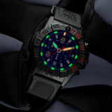 Luminox Navy SEAL Red Bull Ampol Racing Edition Men's 43mm Quartz Chronograph Watch XS.3581.EY.ARB shown in a motorsport-inspired setting. This limited edition chronograph features Red Bull Ampol Racing branding, a lightweight CARBONOX™ case and 200m water resistance.
