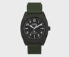 This angle highlights the date window and luminous dial markers against the brushed case. The green silicone strap complements the case's understated, rugged design.